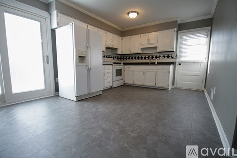 A kitchen with white appliances and cabinets is empty and ready for decorating.