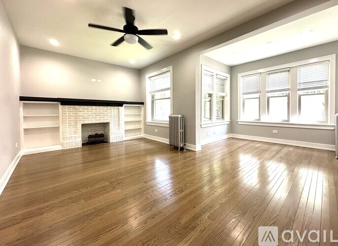 A spacious room with wood flooring and a fireplace.