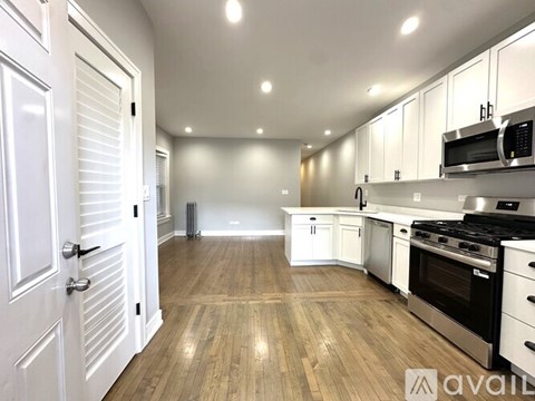 A kitchen with white cabinets and a wooden floor.