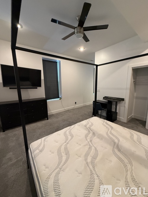 A bedroom with a large bed and a ceiling fan.
