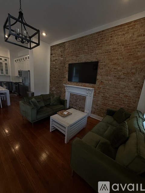 A living room with a brick wall and a flat screen TV mounted above a fireplace.
