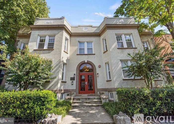 A large, two-story house with a red front door and a stone pathway leading to it.