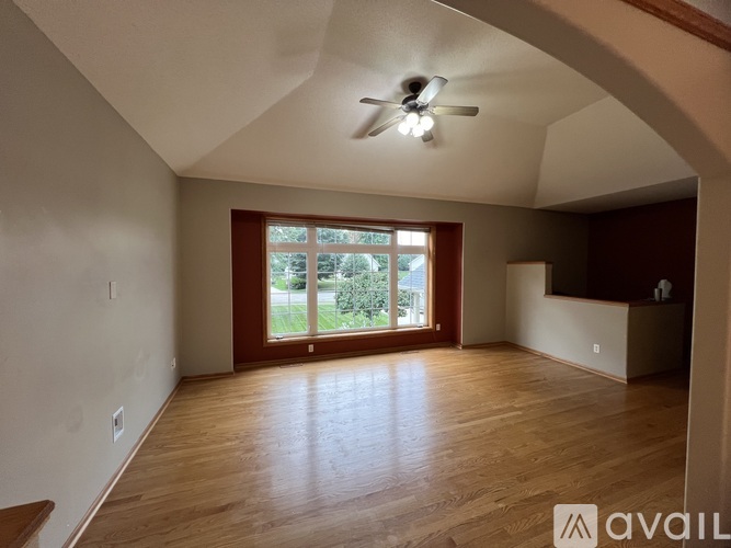 A spacious room with wooden floors and a ceiling fan.