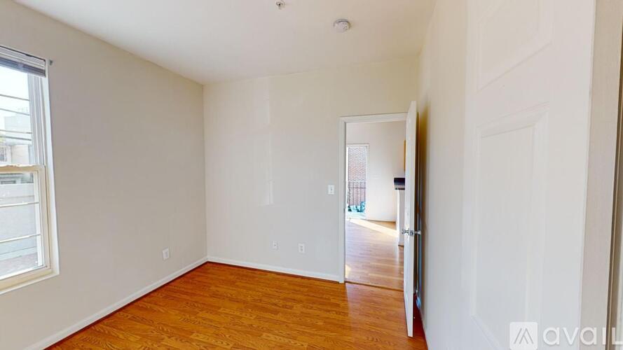 A room with wooden floors and white walls, with a door on the right side.