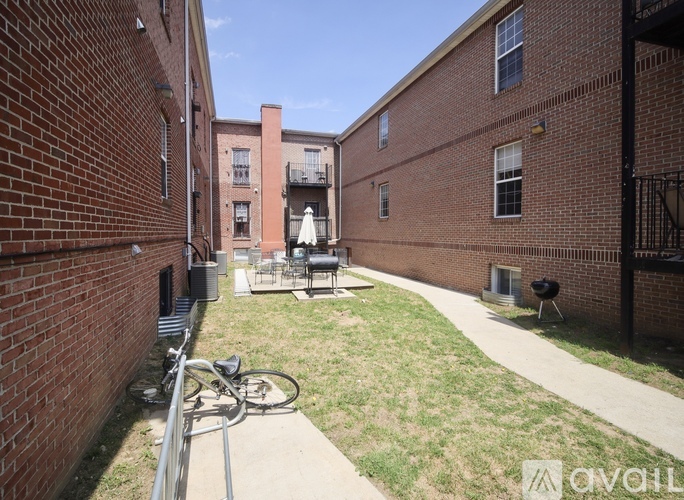 A bicycle is parked on a sidewalk in a courtyard between two brick buildings.
