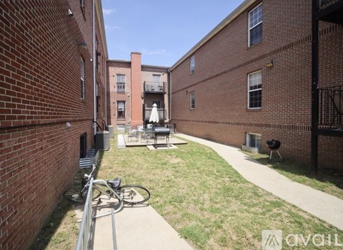 A bicycle is parked on a sidewalk in a courtyard between two brick buildings.