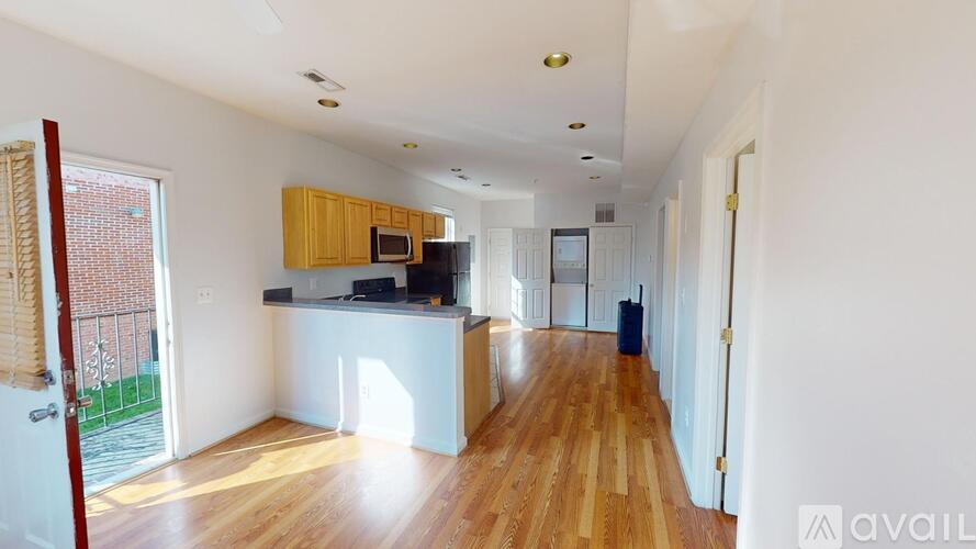 A spacious kitchen with wooden floors and white walls.