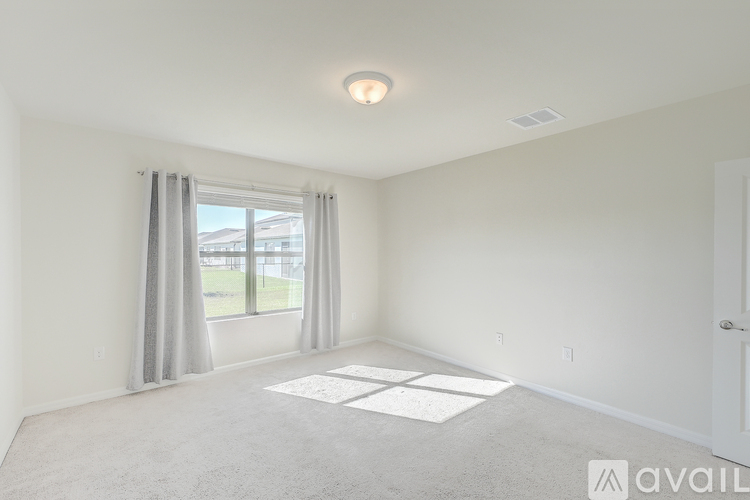 A spacious room with a window and a carpeted floor.