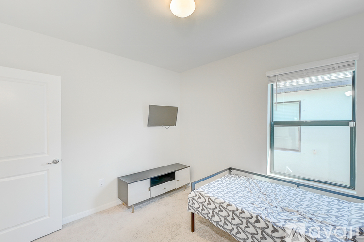 A bedroom with a bed, a window, and a white door.