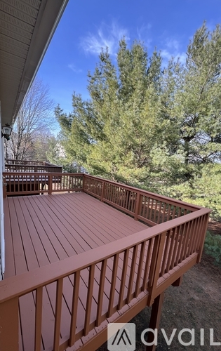 A wooden deck with a railing and trees in the background.