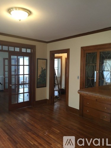 A room with wooden floors and a window with a view of a balcony.