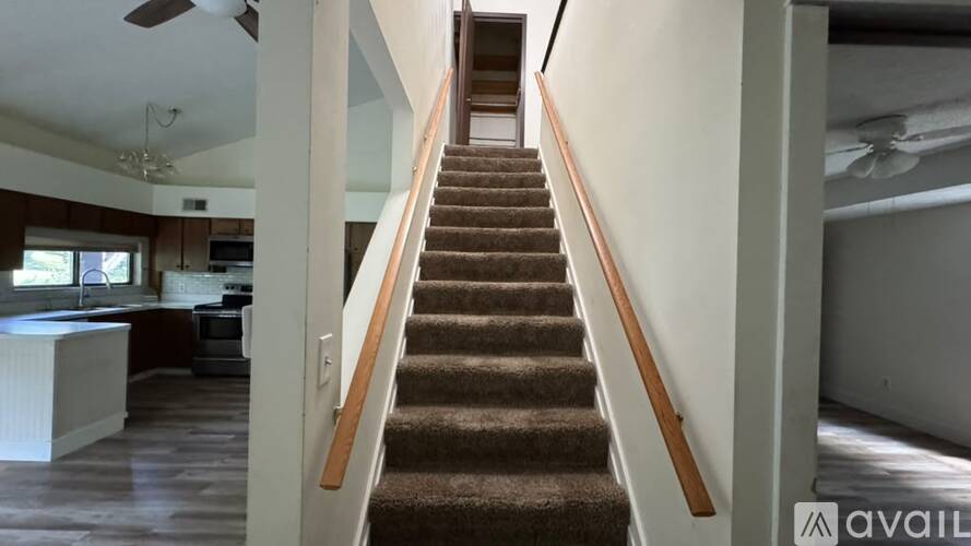 A staircase with wooden handrails leads up to a living room.