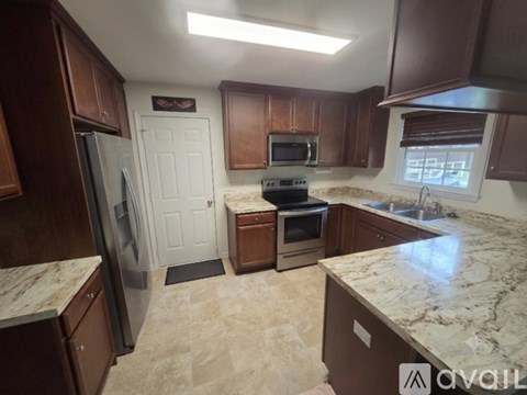 A kitchen with brown cabinets and a marble countertop.