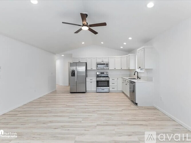 A spacious kitchen with white cabinets and a ceiling fan.