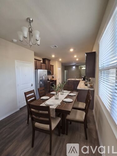 A dining room with a table set for four and chairs around it.