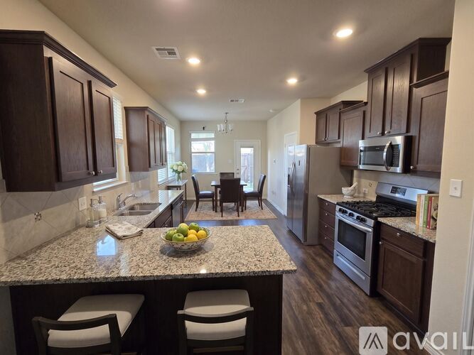 A kitchen with dark wood cabinets and a granite countertop.