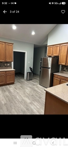 A kitchen with wooden cabinets and a stainless steel refrigerator.