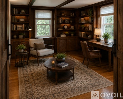 A cozy living room with a coffee table in the center and a bookshelf filled with various items.