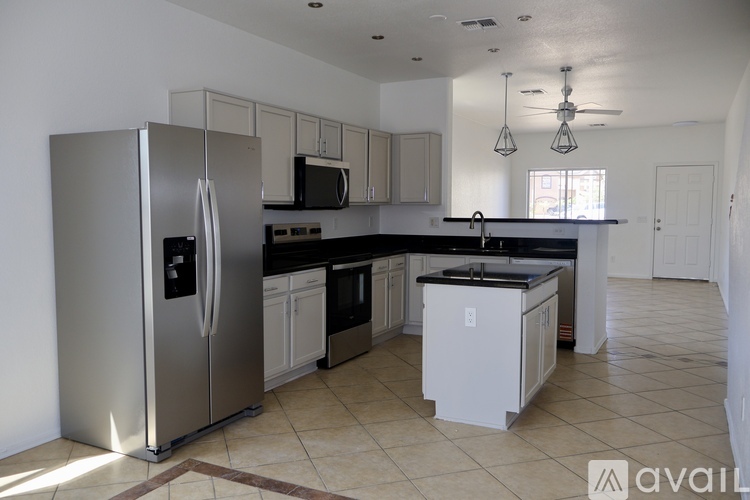 A kitchen with a stainless steel refrigerator and white cabinets.