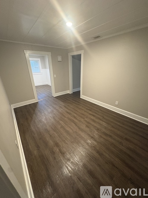 A room with wooden flooring and a door on the right.
