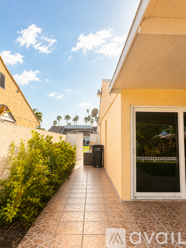 A tiled walkway leads to a house with a glass door.