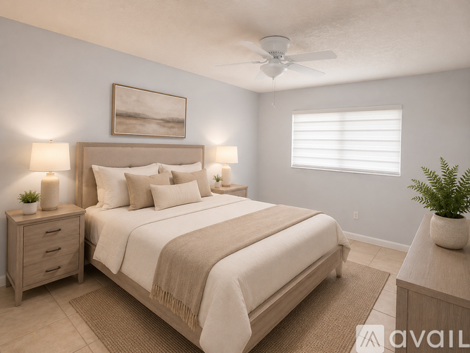 A well-lit bedroom with a large bed, a ceiling fan, and a nightstand with a plant on top.