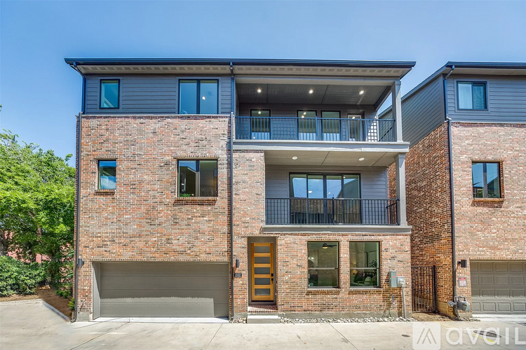 A modern two-story brick house with a balcony on the upper floor.