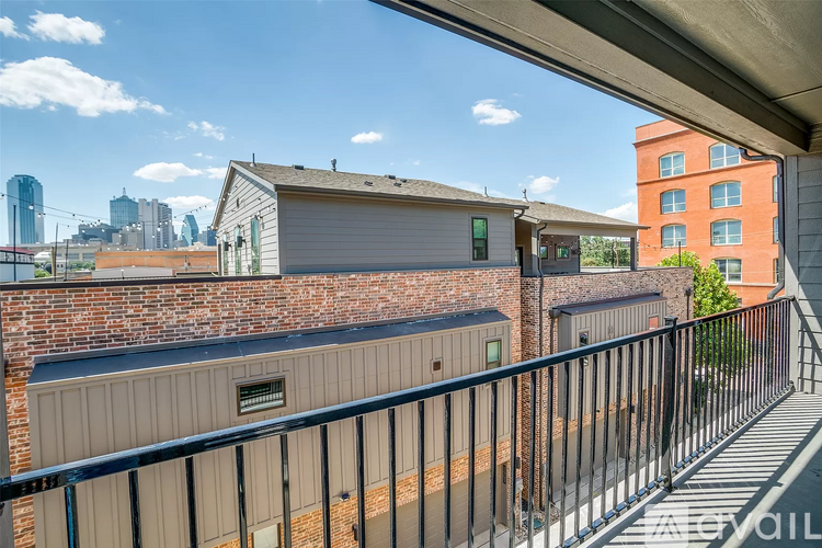 A balcony with a metal railing overlooks a brick building and a city skyline.