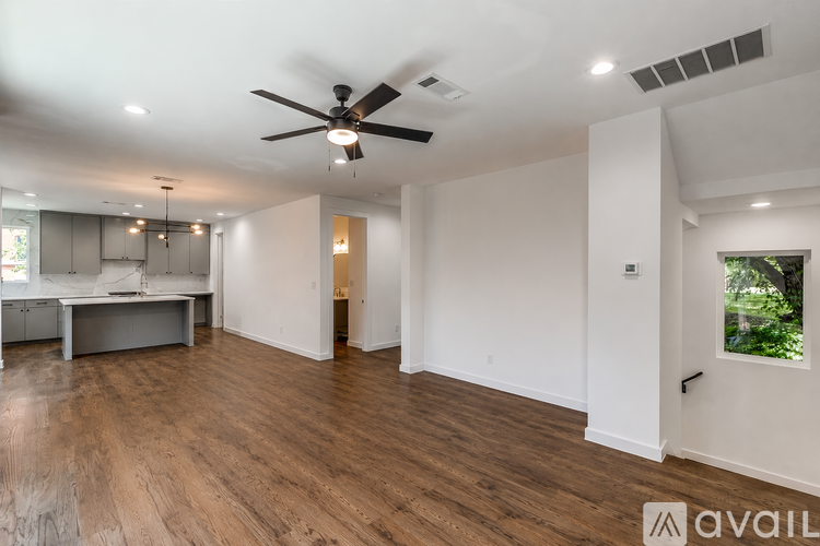 A spacious room with a ceiling fan and wooden flooring.