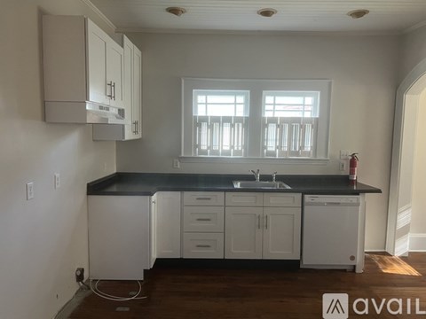 A kitchen with white cabinets and a black countertop.