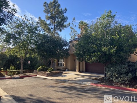 A house with a driveway and trees in front of it.