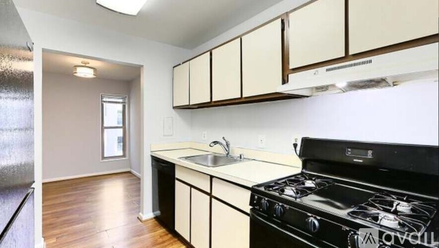 A kitchen with a black stove top oven and white cabinets.