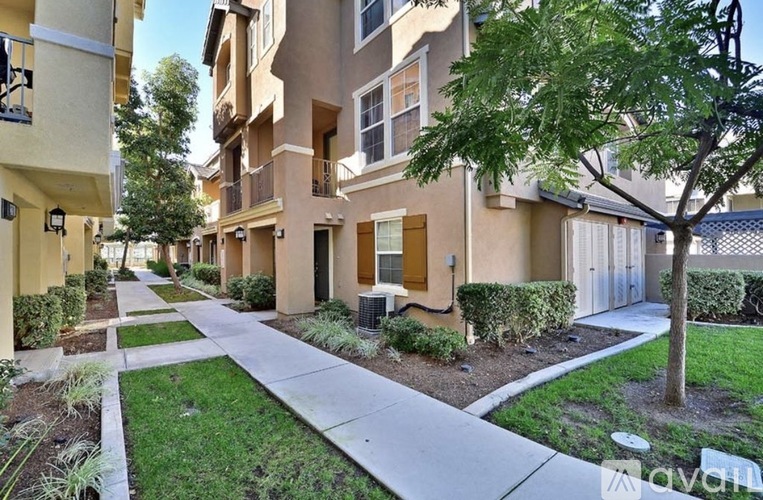 A row of apartment buildings with a sidewalk in front.