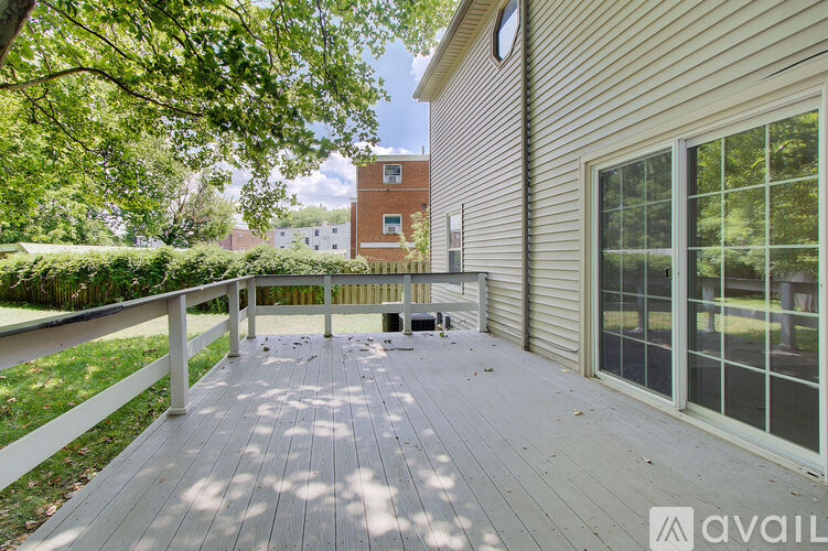 A wooden deck with a white railing and a building in the background.