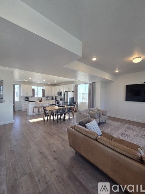 A modern living room with a brown sofa and a dining table with chairs.
