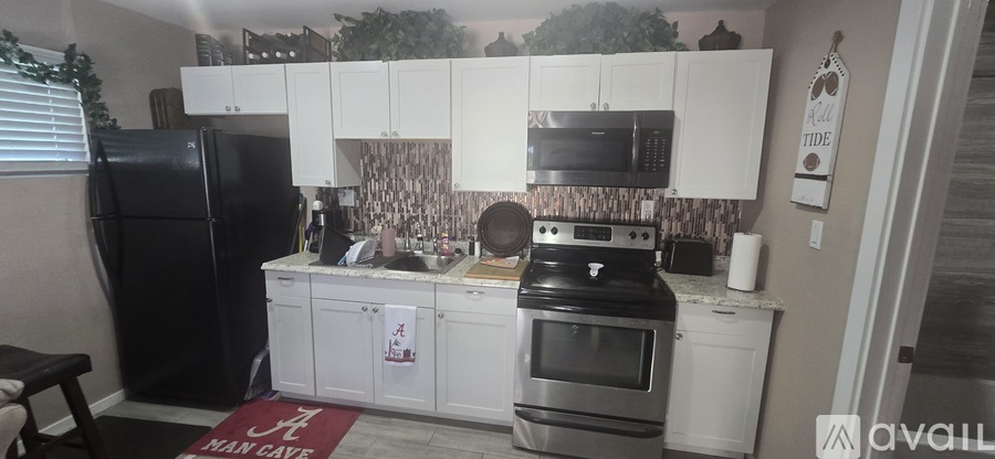 A kitchen with white cabinets and a black fridge.