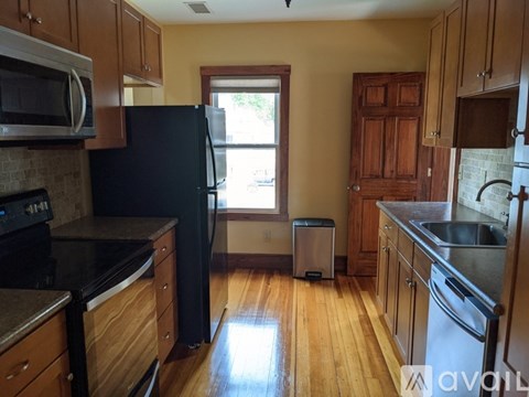 A kitchen with a black refrigerator and wooden cabinets.