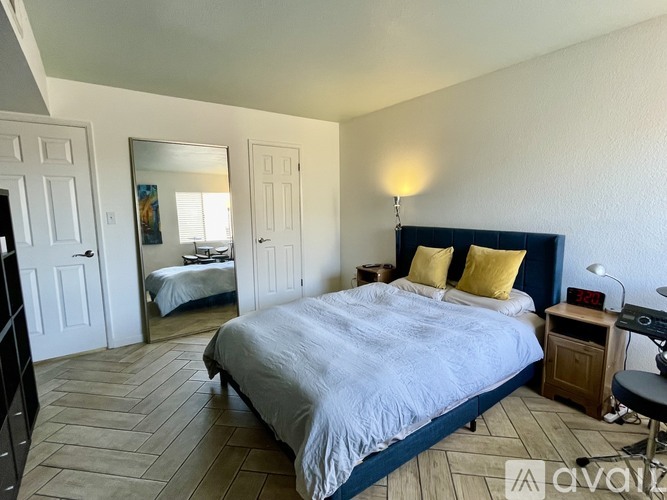 A bedroom with a large bed and a mirror on the wall.