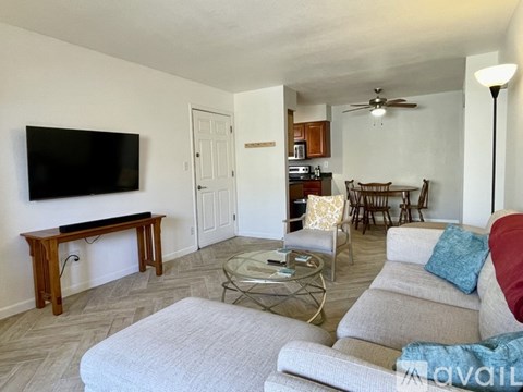 A living room with a grey couch and a television on the wall.