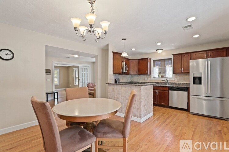 A kitchen with a table and chairs in the foreground and a refrigerator in the background.