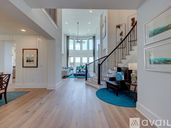 A spacious living room with a staircase and a painting on the wall.