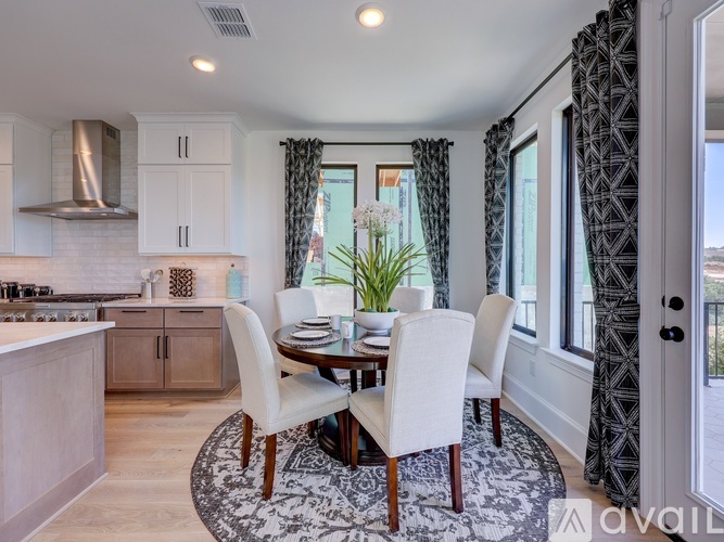 A dining room with a table set for four and a kitchen area in the background.