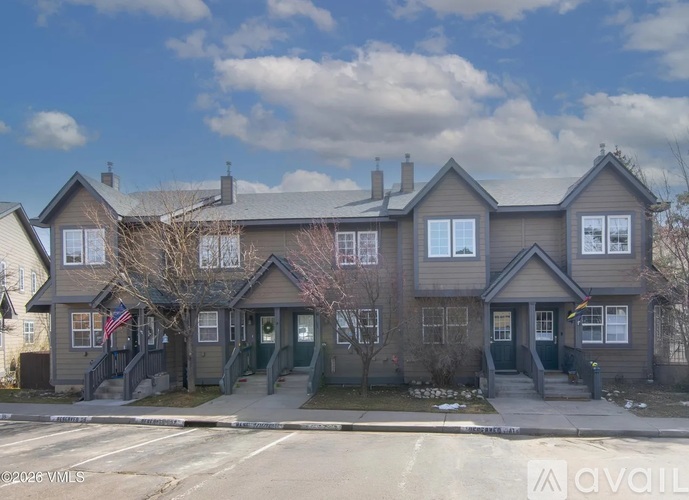 A two-story house with a grey facade and a flag on the front porch.