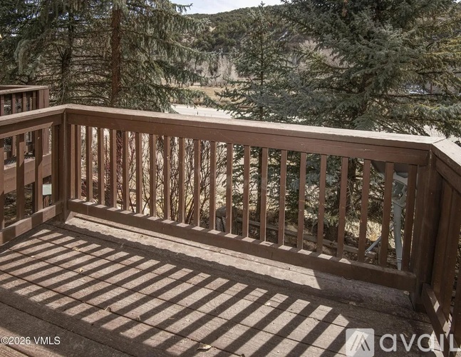 A wooden deck with a railing overlooking a forested area.