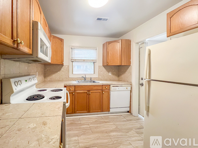 A kitchen with wooden cabinets and a white stove top oven.