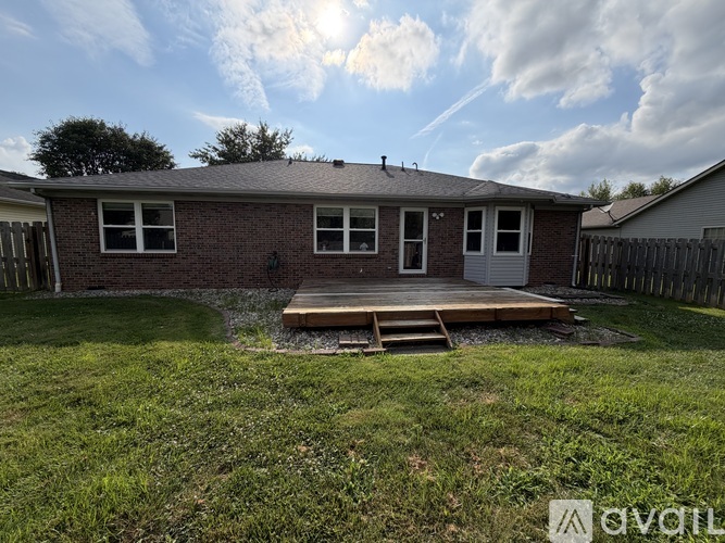 A small brick house with a white door and windows is surrounded by a grassy yard.