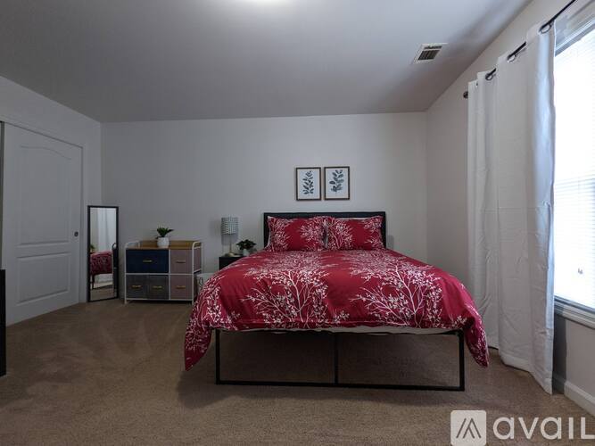 A bedroom with a red bedspread and a bed with a black frame.