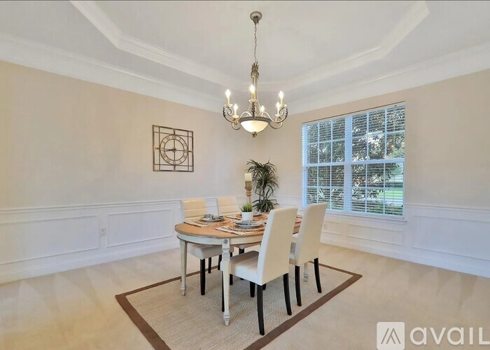 A dining room with a table set for four and a chandelier hanging from the ceiling.