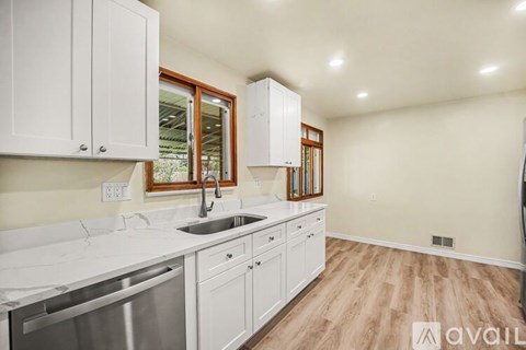 A kitchen with white cabinets and a wooden floor.
