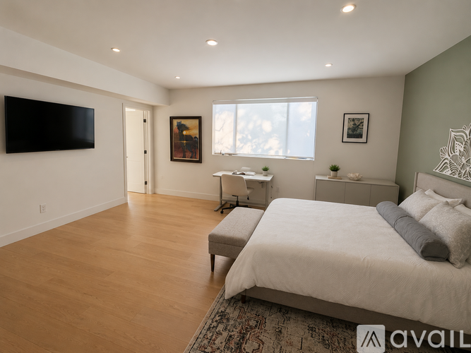 A bedroom with a large bed and a flat screen TV mounted on the wall.